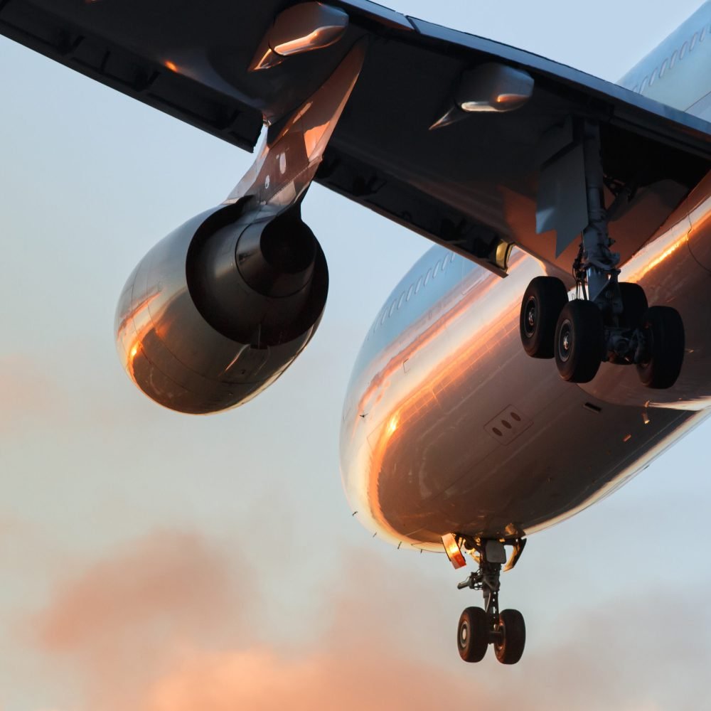 Airplane ready to landing or takeoff at sunset, bottom view, close up of wing, engine and chassis.